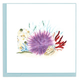 Blank greeting card of a quilled purple sea urchin under water surrounded by sand, barnacles and coral