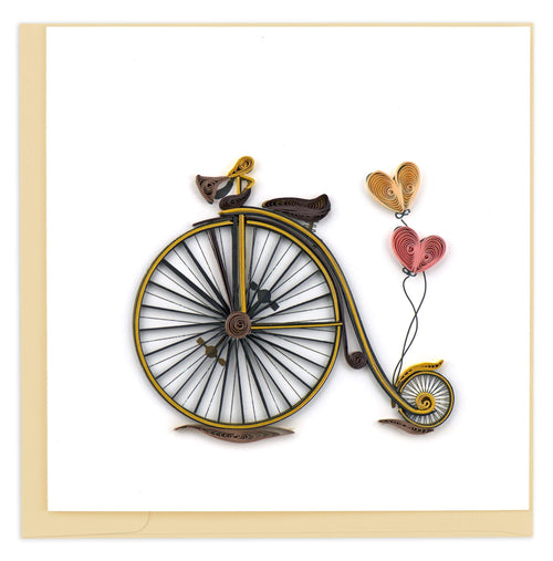 A gold bike with a larger front wheel,smaller back wheel, and heart balloons trailing behind.